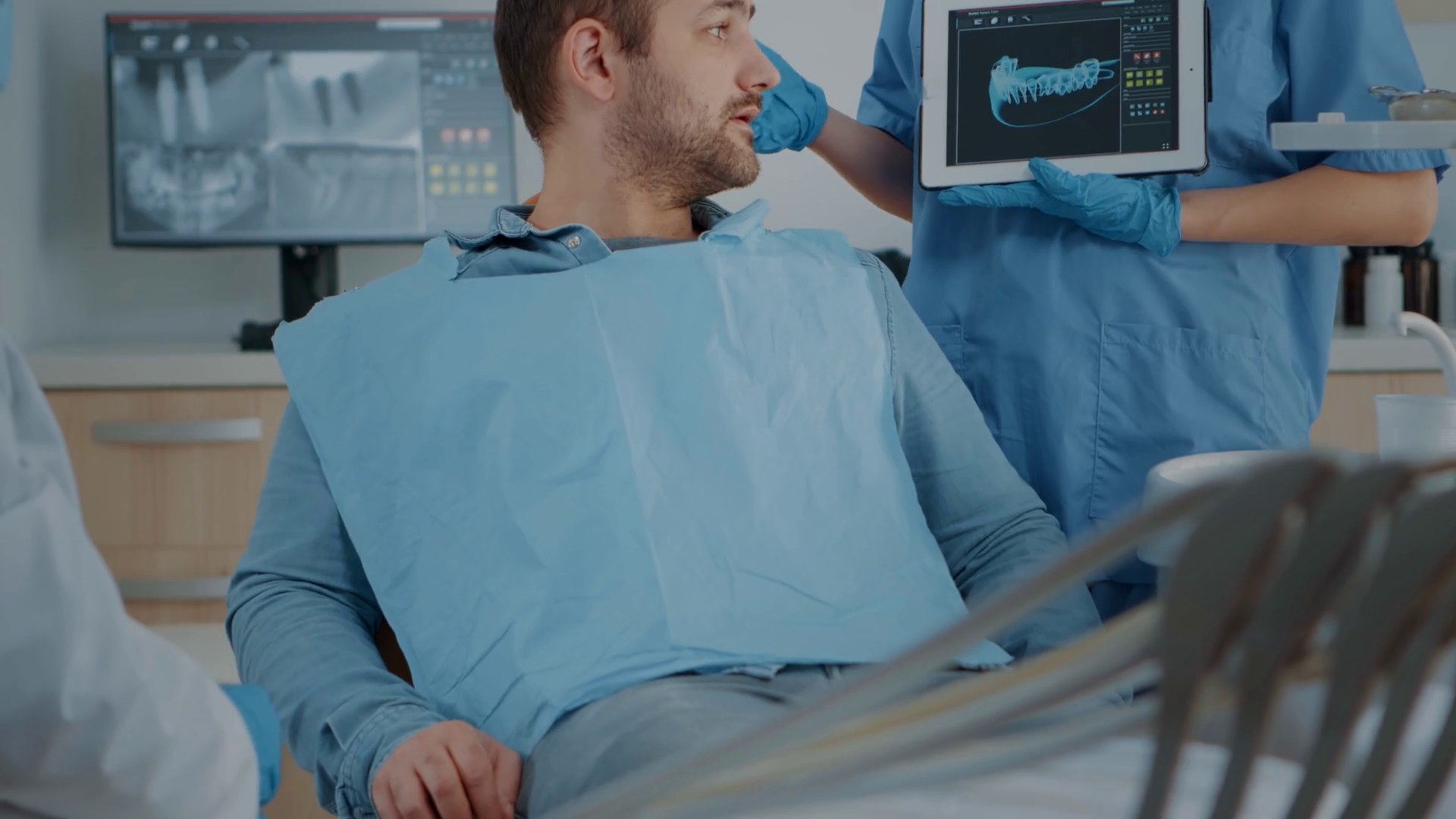 Dentistry assistant showing x ray scan results on tablet to patient
