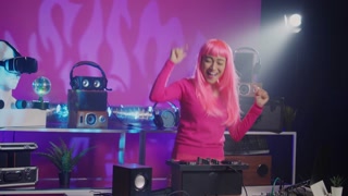 Cheerful dj performing electronic music during concert in nightclub, enjoying dancing and having fun with fans during performance. Asian performer mixing sound using professional mixer console