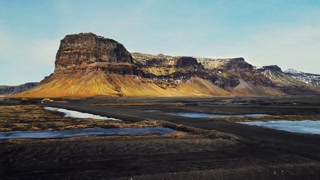 Drone shot of majestic mountain in iceland, spectacular roadside and snowy fields. Icelandic massive hills and brown frozen lands in scandinavian landscapes. Slow motion.