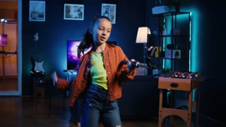 Panning shot of young media star dancing in apartment, recording video with phone on selfie stick for gen z internet fans. Excited kid