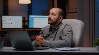 Businessman on company teammeeting conference videocall online meeting remotely discussing management strategy late at night in startup office. Tired entrepreneur on internet web webinar remote call