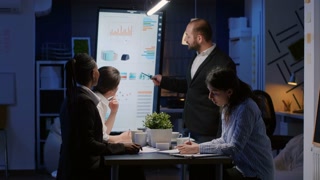 Entrepreneur man brainstorming management strategy working hard in meeting office room late at night. Diverse multi-ethnic business team looking at financial company presentation on monitor