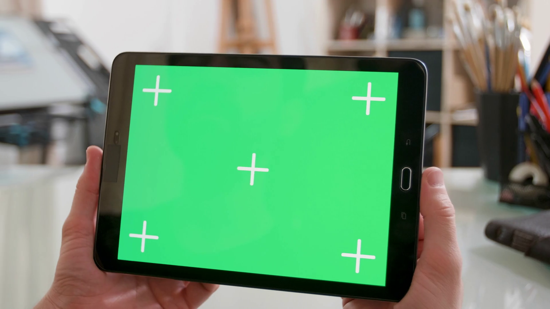 Holding a tablet with green screen on in a artists Male hands