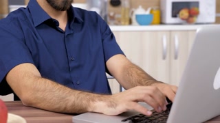 Man hand in close up typing on computer keyboard in the kitchen. Dolly slider 4K footage