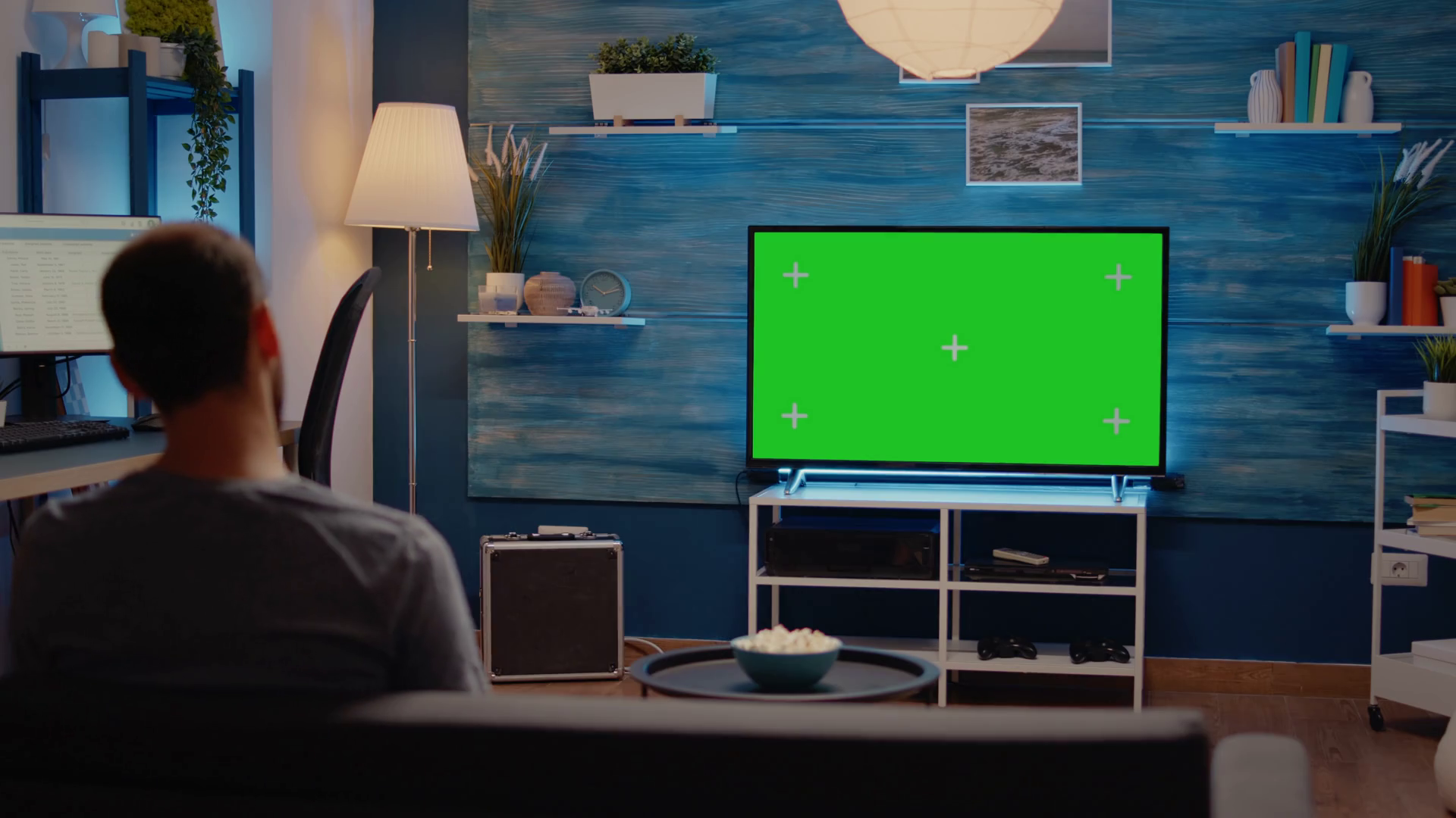 Man watching television with green screen display switching channels