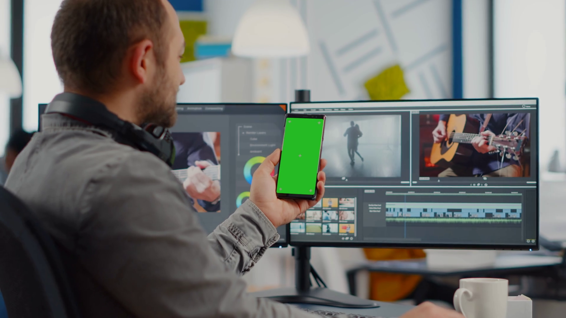 Video editor talking on video call holding smartphone with green screen