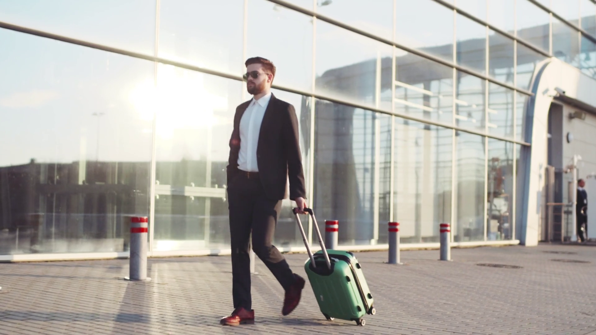 Stylish young bearded man in sunglasses exiting the airport terminal