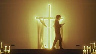Devout Christian Praying with Bible Before Glowing Cross