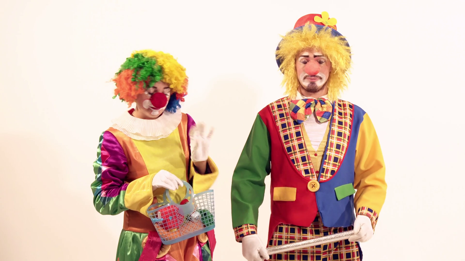 Happy circus clown showing what she has in her basket to the other smiling clown Stock Video