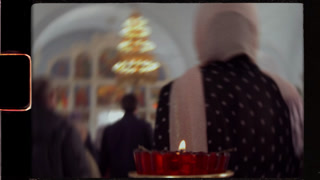 Orthodox christian woman praying with candle inside church