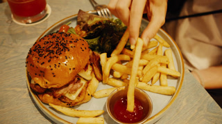 Woman's hand dipping french fries into ketchup
