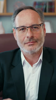 Portrait of good-looking positive high-skilled successful bearded ceo in business suit which taking off his eyeglasses and looking into