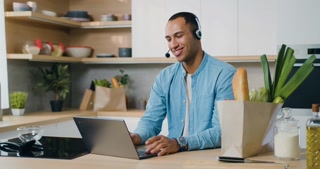 African man in headphones using a laptop computer and with a smile communicates via video chat. Webinar, videocall event, video conference call communication, solve business remotely concept.