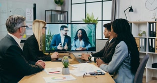 Close up of good-looking confident qualified multiracial businesspeople which sitting in boardroom during conference chat meeting with male and black-skinned female colleagues