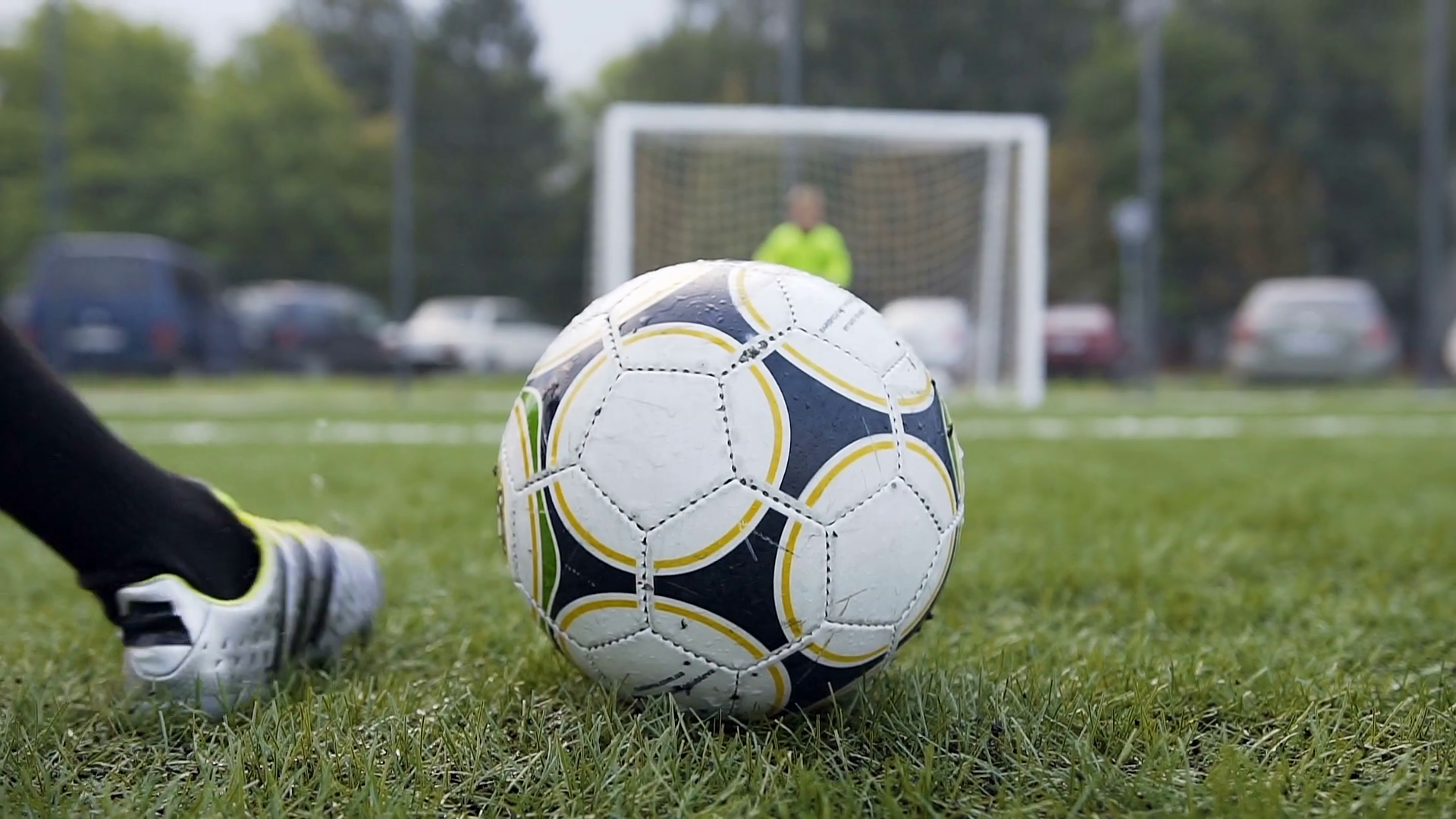 Boy legs kicking soccer ball to the gates and goalkeeper catching the