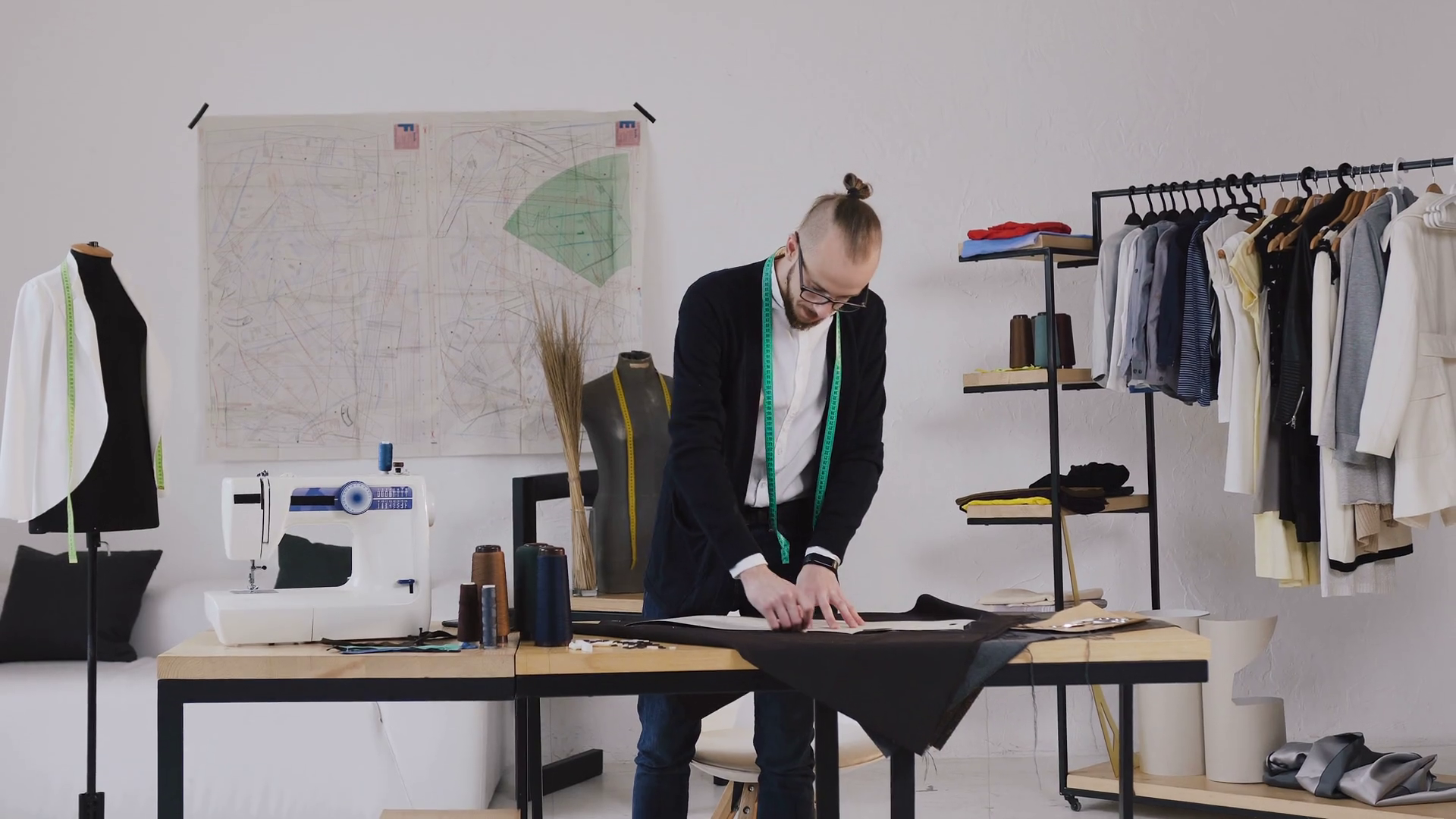 Clothing designer and tailor is working with measurements on a studio table. Manufacturer of