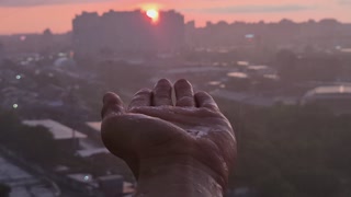 Raindrops dripping on a man's palm at sunset, close-up