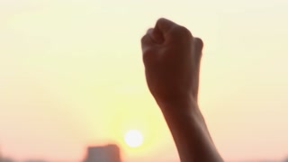 Protestant's hand clenched into a fist against the sky, close-up
