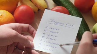 A man holds a grocery list in his hands and checks it against the actual availability