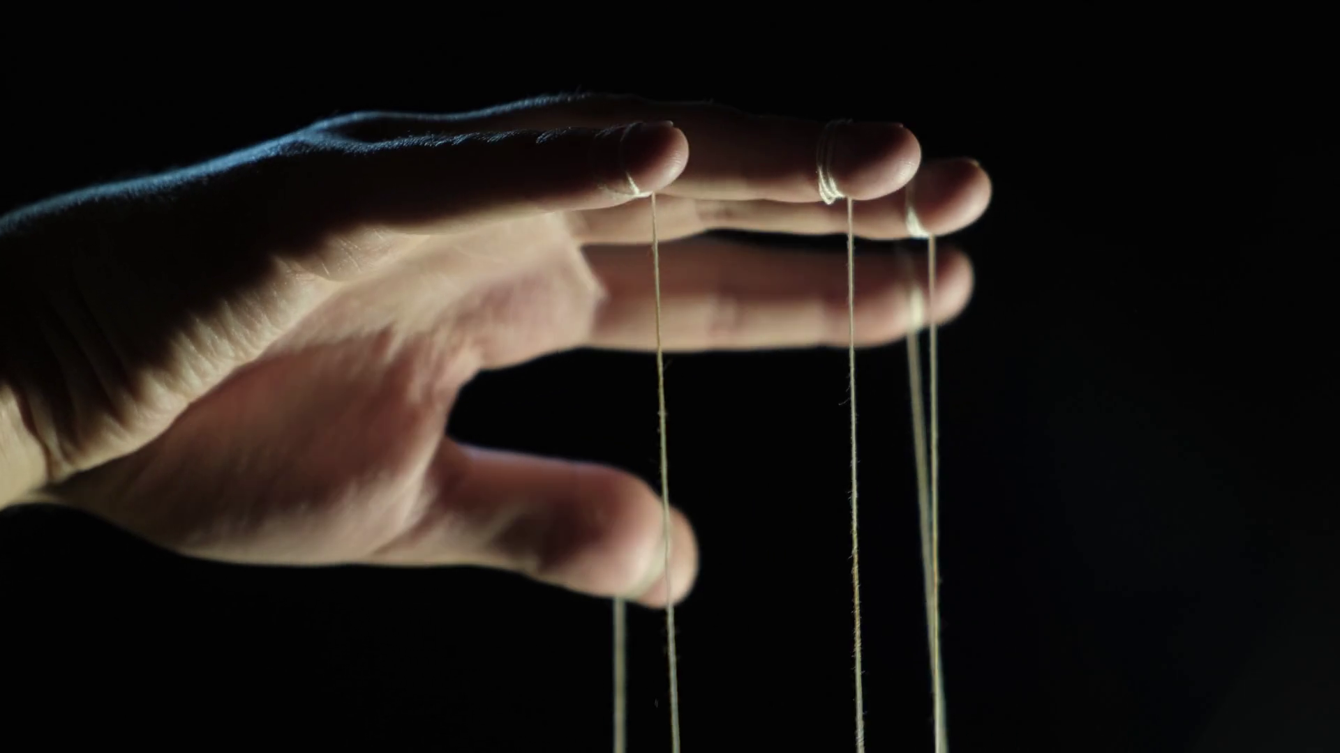 The puppeteer's hand controls the puppets on strings. Manipulation