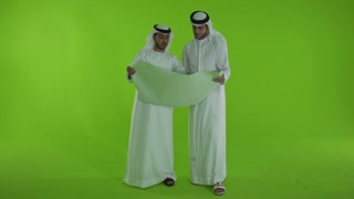 Emirati businessmen discussing over blueprint.