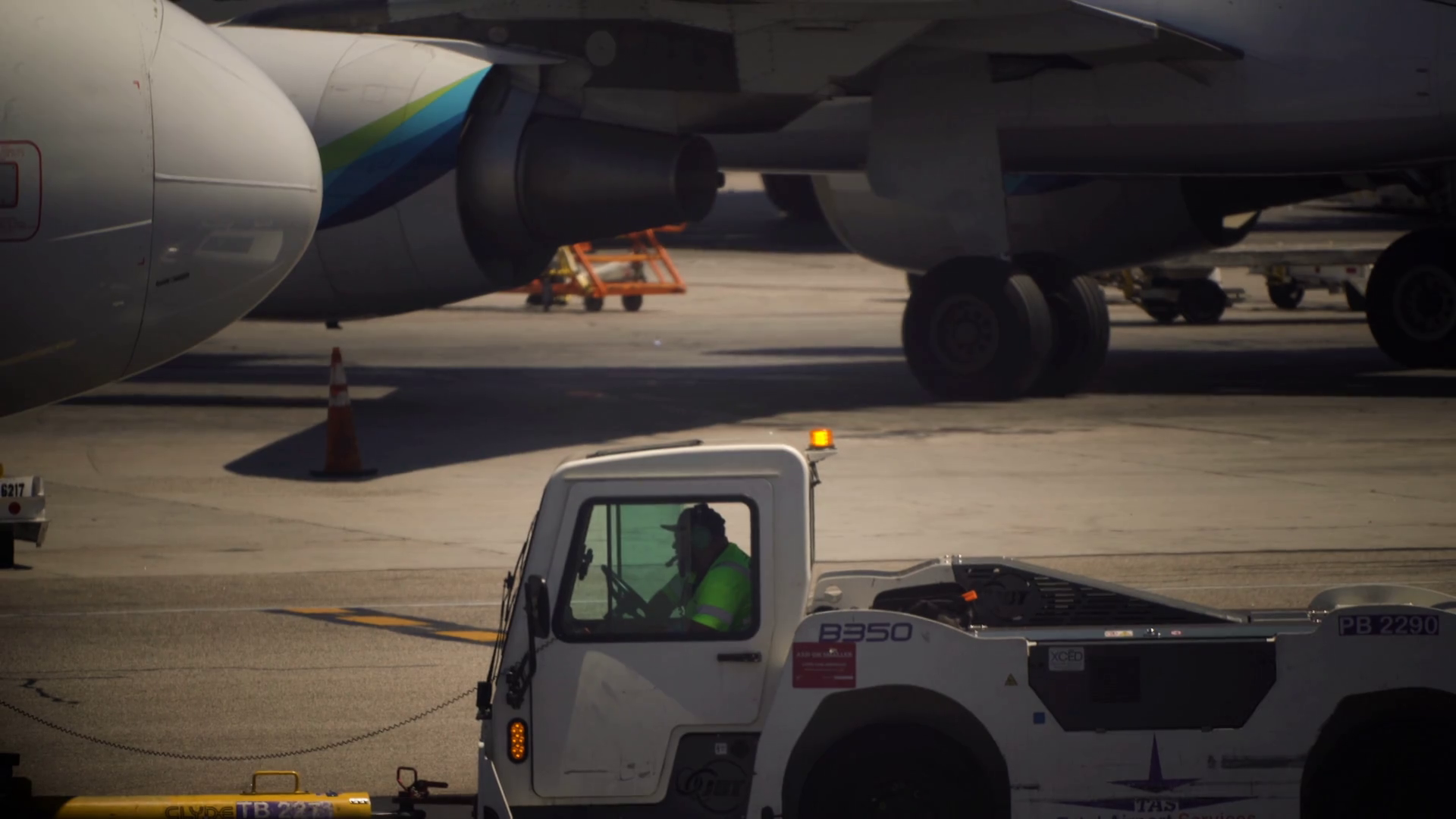 Ground Crew workers on airport tarmac attach tow vehicle to passenger