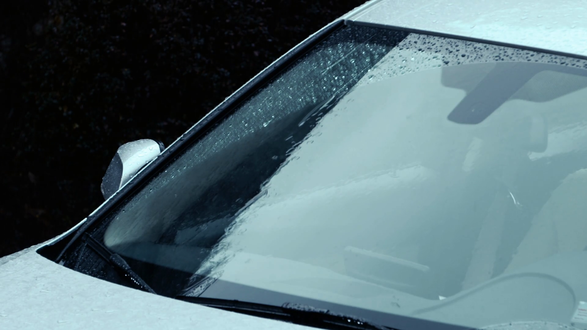 Telephoto Raindrops splash and streak down windshield of car during