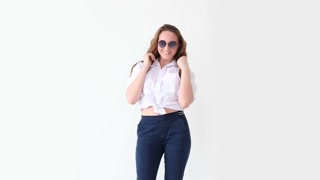fashion of modern youth. stylish girl posing against white wall in jeans, white shirt, with leather backpack and glasses.