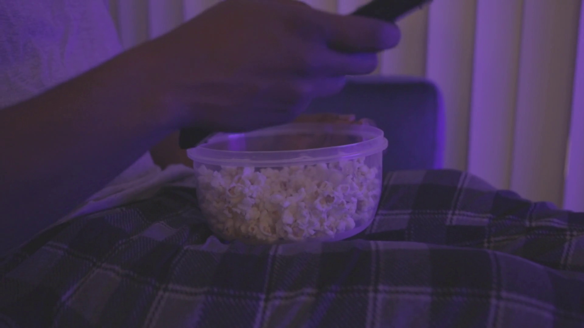 Black man eating popcorn late at night while watching T.V. Stock Video