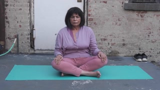 Elderly Indian woman doing yoga outside her home. 