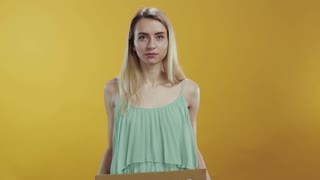 A Woman Holding a Cardboard Box Stylishly in Front of a Vibrant Yellow Background