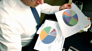 Businessman working on graphs in the restaurant, steadycam shot