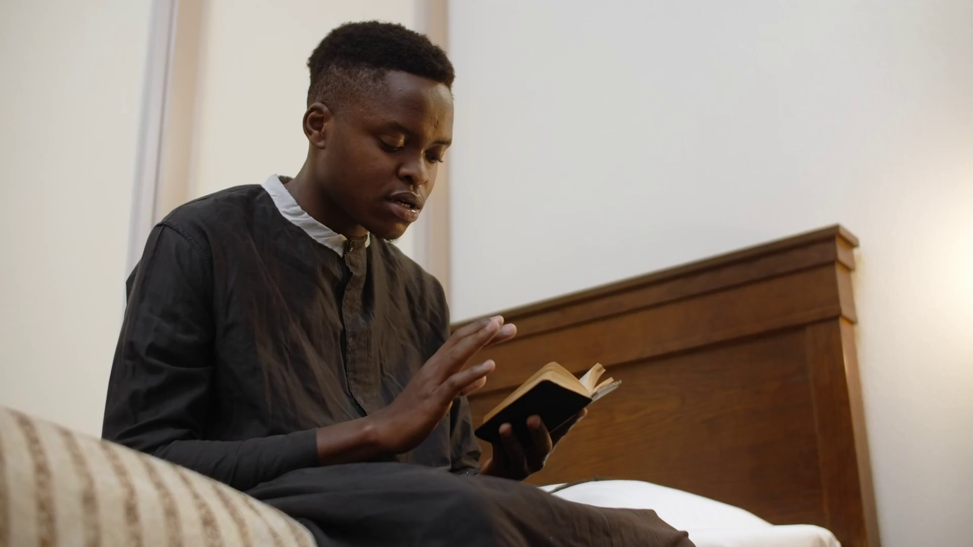 African american young catholic priest reads the bible at his room, seminarist is reading a book