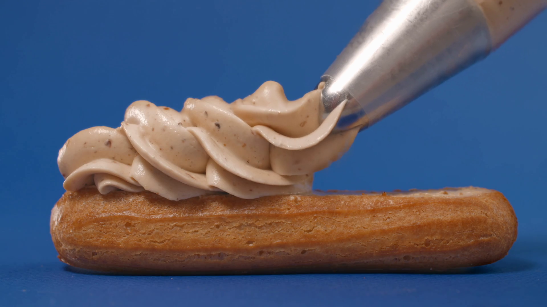 Confectioner squeezes custard from pastry bag to the eclair, cream on