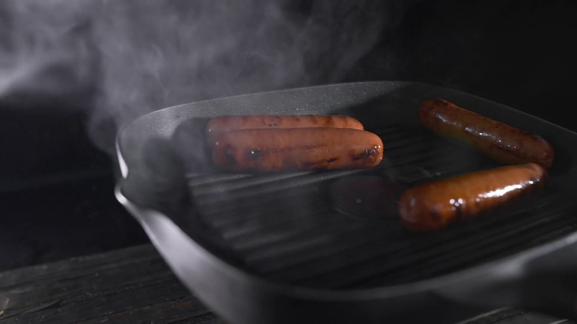 Sausages is roasting with smoke on the hot grilling pan, cooking food