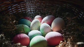 A collection of beautifully colored eggs nestled in a basket filled with shredded paper. The vibrant hues of blue, pink, green, and yellow