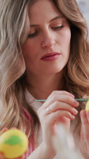 Easter egg painting scene with woman concentrating on delicate art