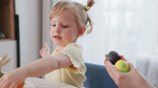 Toddler girl engages in Easter egg decorating