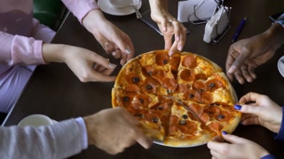 friends sharing a pizza in a restaurant - Hands taking a pizza margherita slice - Concepts about food,nutrition,party and friendship.