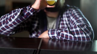 Bearded man drinking beer and enjoying a drink at the pub bar. Male guest tries a glass of beer