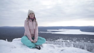 Girl sitting on the snowy stones and relaxing