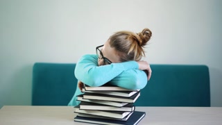 Tired, angry, exhausted student lowered her head on a stack of books. You have to read a lot of books. Much work. Shut. Education, people, children and learning concept.