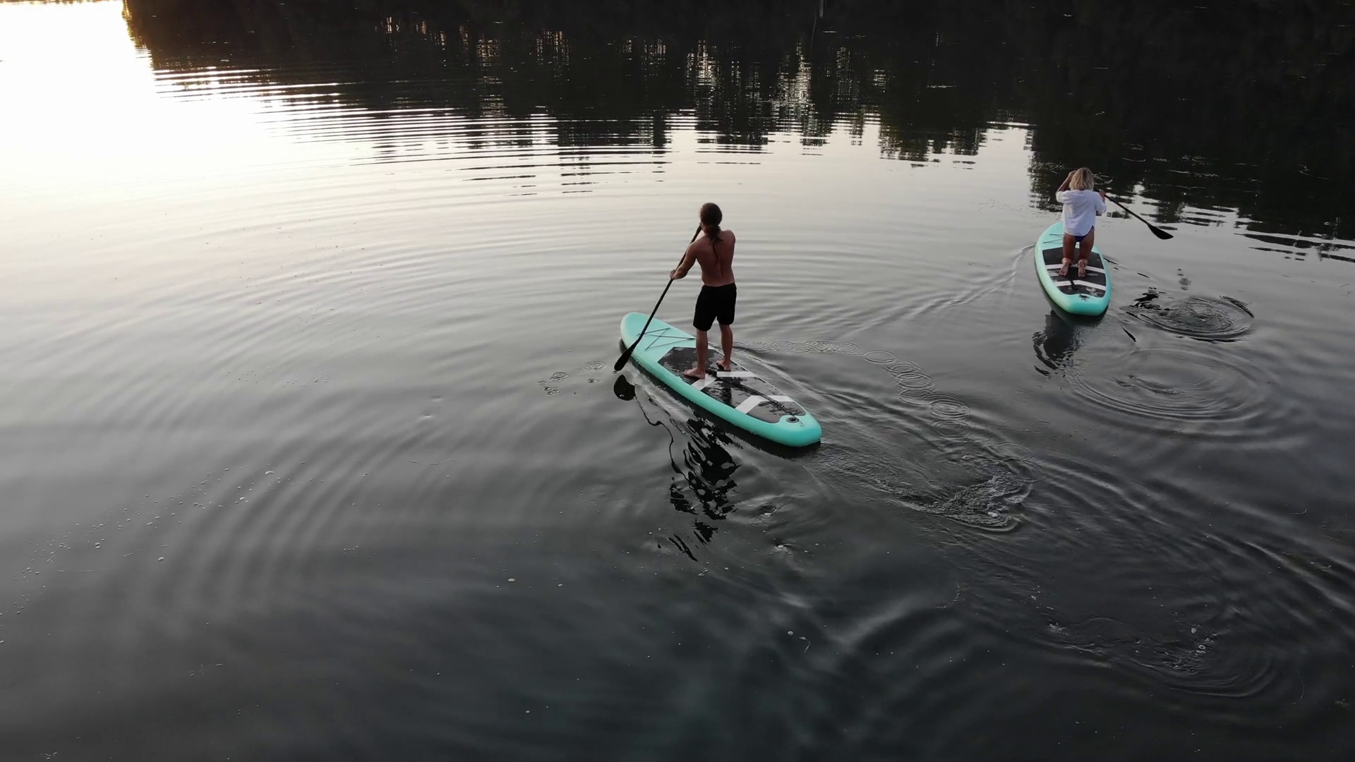 Couple of surfers paddling on surfing boards, drone shooting of people