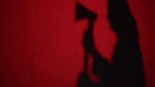 Creepy death silhouette running for victim with axe on red background. Mystical scary murderer, maniac catching up woman. Halloween costume of killer. Horror scene movie of psycho serial.