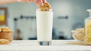 Eating cookie with milk in glass cup close-up. Glass with yogurt, dairy products concept. Drinking fresh lactose-free milk in morning.