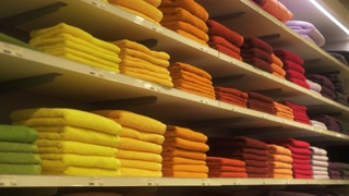 Stack of colorful towels in the department store storage. Many pile of cotton towels in store shop. Concept of shopping, buy and sell e-commerce.