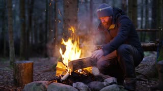 adult-man-fires-up-campfire-outdoor-in-t