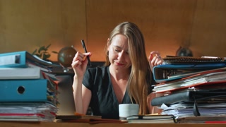 PAPERWORK CONCEPT: Busy 30s accounting manager works from home surrounded by documents.