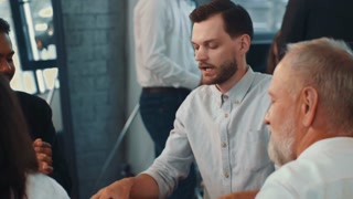 Serious male data scientist works together in team. Colleagues celebrate positive results and clapp together.