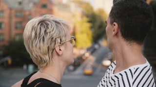 Young woman and man embracing on a bridge, enjoying city scenery